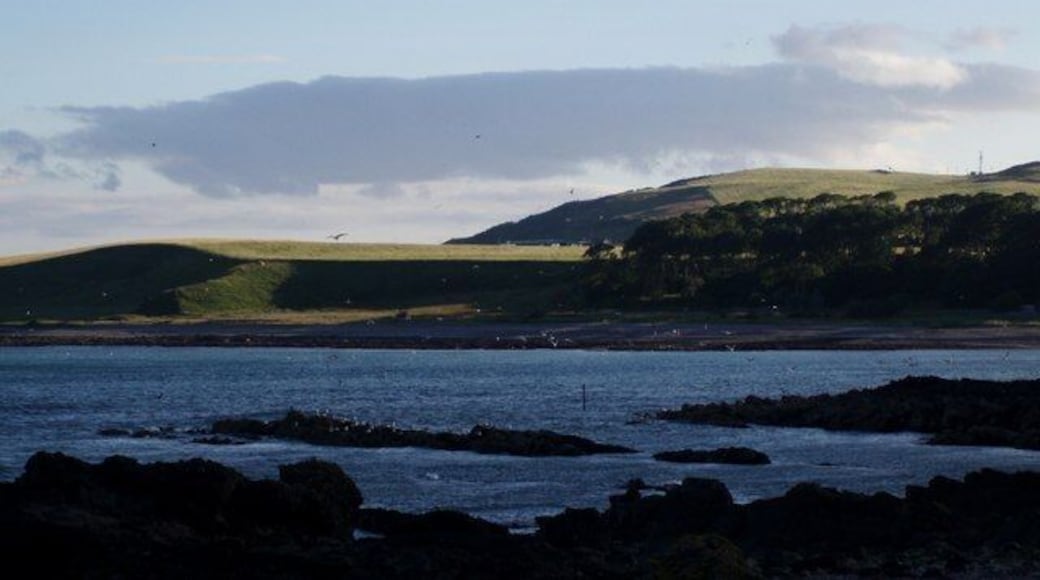 Across Inverbervie Bay to Hallgreen Castle The wave cut platform of the northern end of the bay is in shadow in the foreground. The setting sun catches the raised beach at Hallgreen Castle on the southern side of the bay.