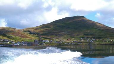 A coastal village with a prominent hill, a castle-like structure, and a body of water.
