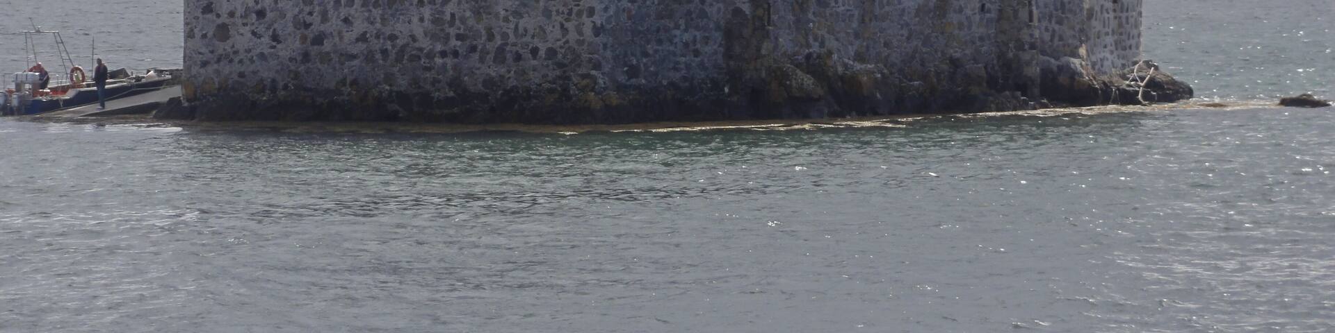 A historic stone castle on a small island surrounded by water.