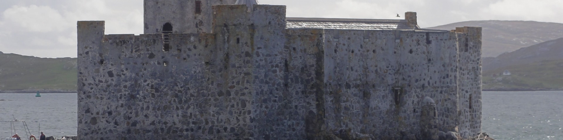 Um castelo de pedra histórico numa pequena ilha rodeada por água.
