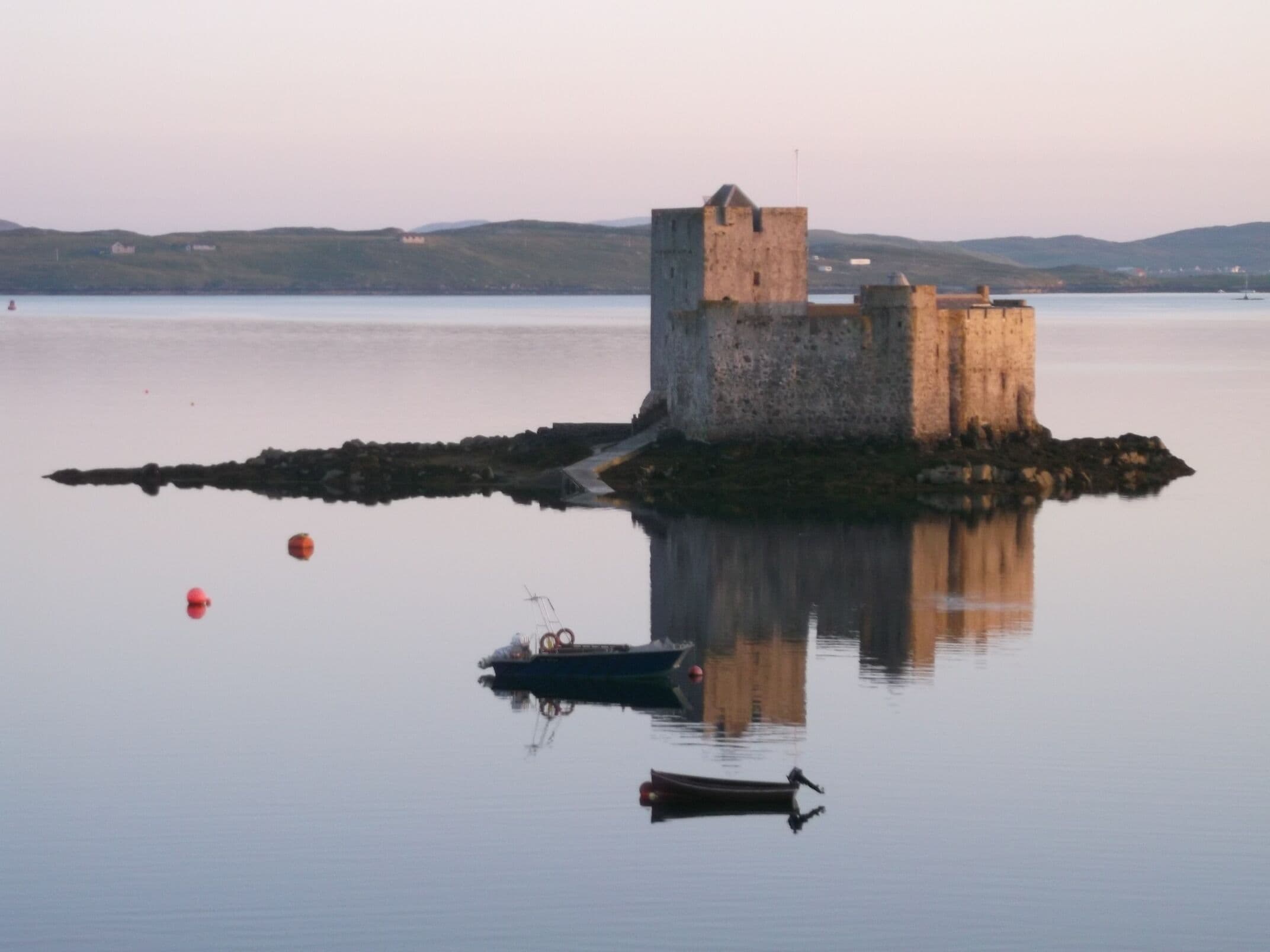 A castle on a small island surrounded by calm water.