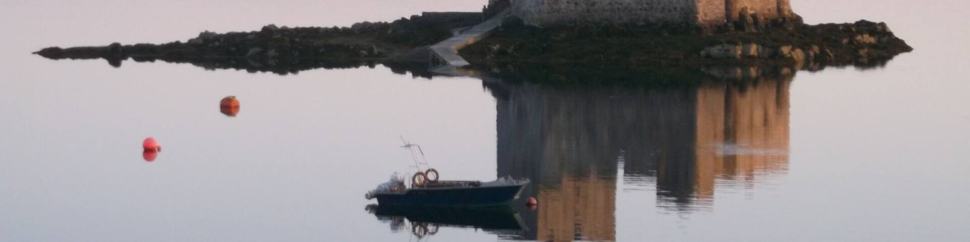 A castle on a small island surrounded by calm water.