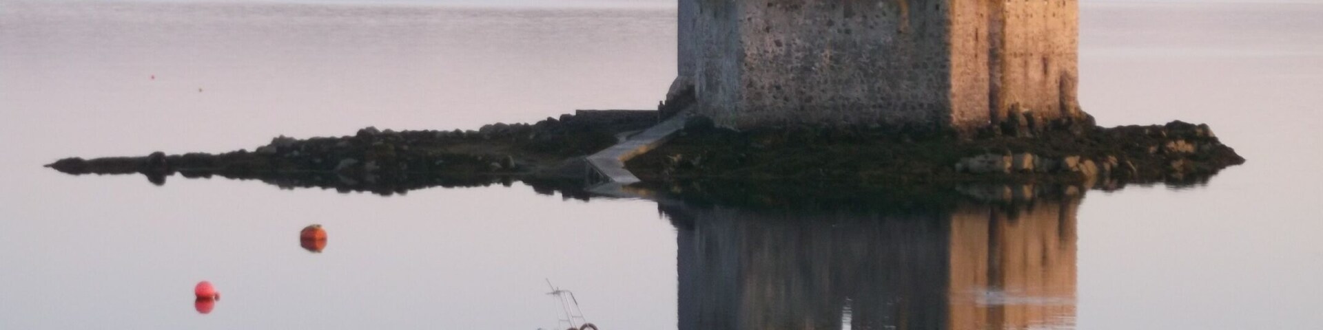 Un castillo sobre una pequeña isla rodeada de aguas tranquilas.