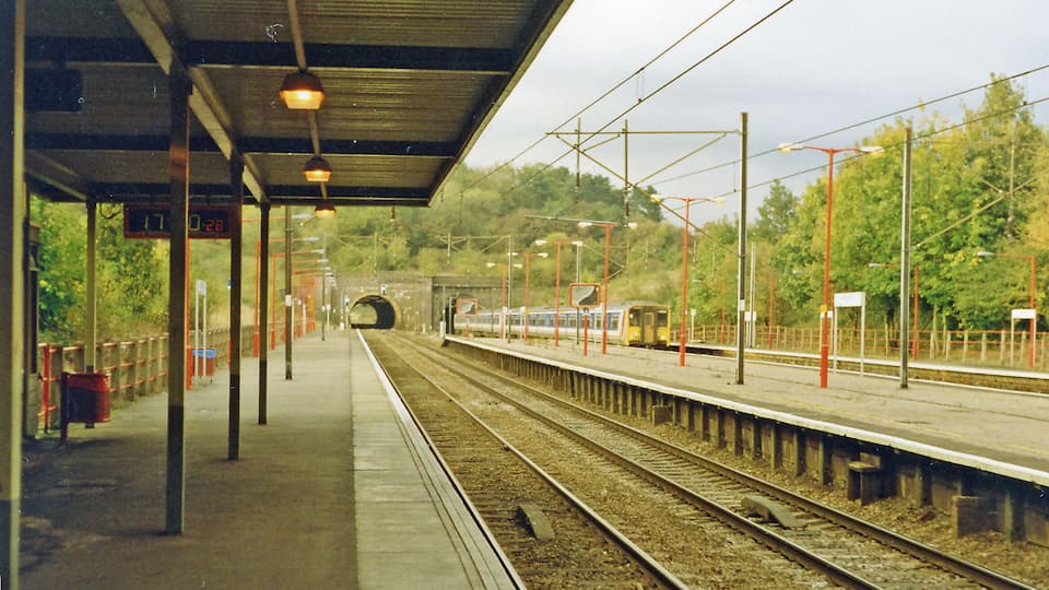 A railway station with a train approaching through a tunnel.