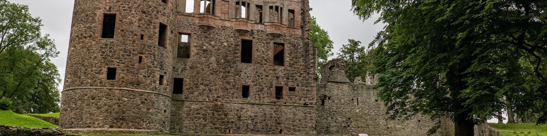 Huntly Castle in Scotland, UK in early evening with a stone wall and tree