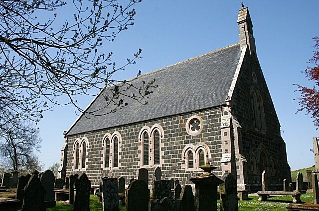 A stone church with a steep roof and arched windows, surrounded by a cemetery.