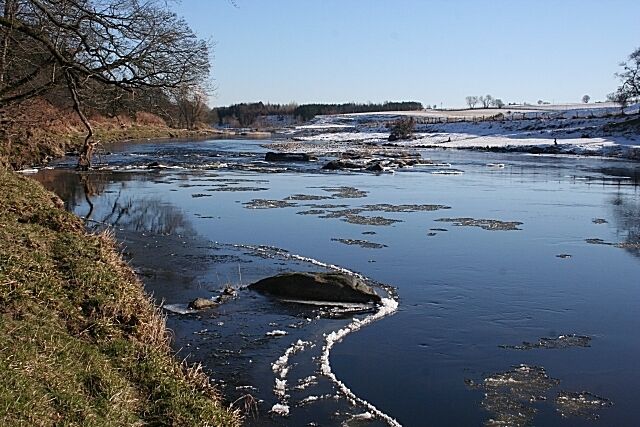 River Deveron This smooth reach of the river ends at the slight rapids just downstream. The shingle bank below the rapids is exposed, suggesting that the river level is not especially high.