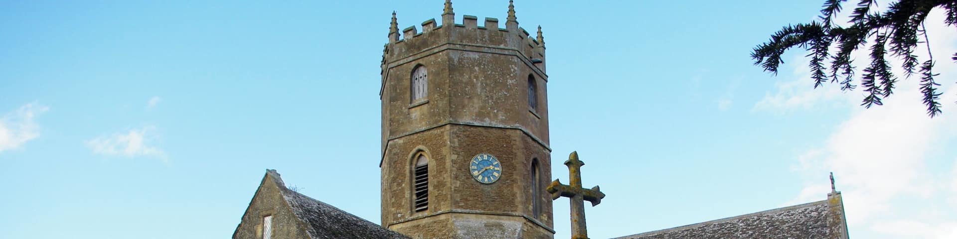 A historic church with a prominent tower and a large cross in the foreground.