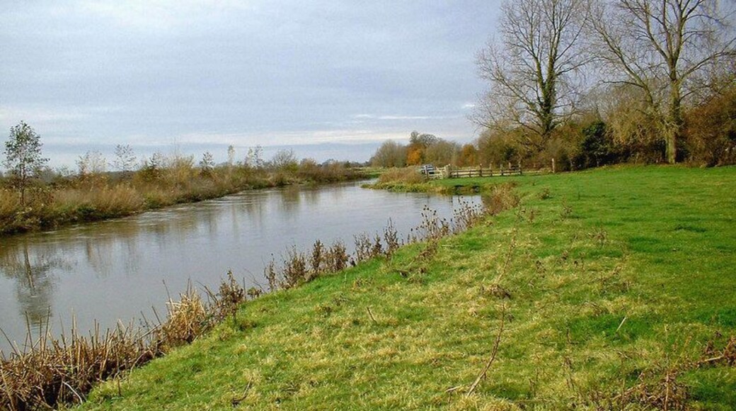 River Thames near Kelmscott In the distance there is a small car park. This is at the end of a lane which comes down here from the village of Kelmscott, or Kelmscot, as it is often spelt. The lane passes the famous Kelmscott Manor and is much used by fishermen. Near here is a field used for caravans in the warmer months of the year.