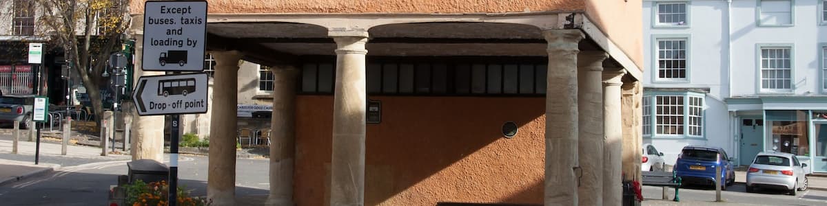 Ein zweistöckiges Gebäude mit einem steilen Dach und einem Schild, das Parkverbote für alle Fahrzeuge außer Bussen, Taxis und Lastwagen anzeigt.