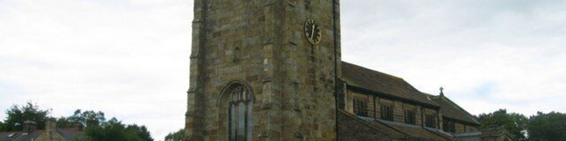 Una iglesia histórica con una torre alta y un cementerio al frente.