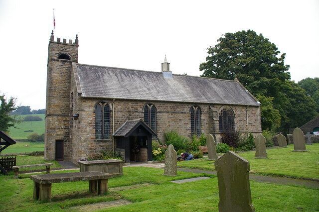 A stone church with a bell tower, surrounded by a cemetery with headstones.