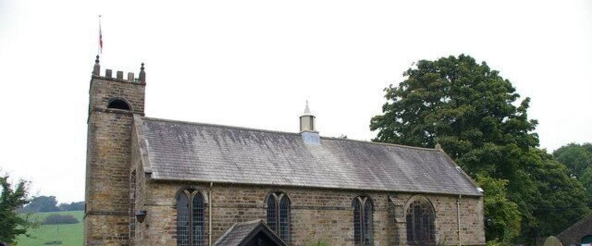 A stone church with a bell tower, surrounded by a cemetery with headstones.