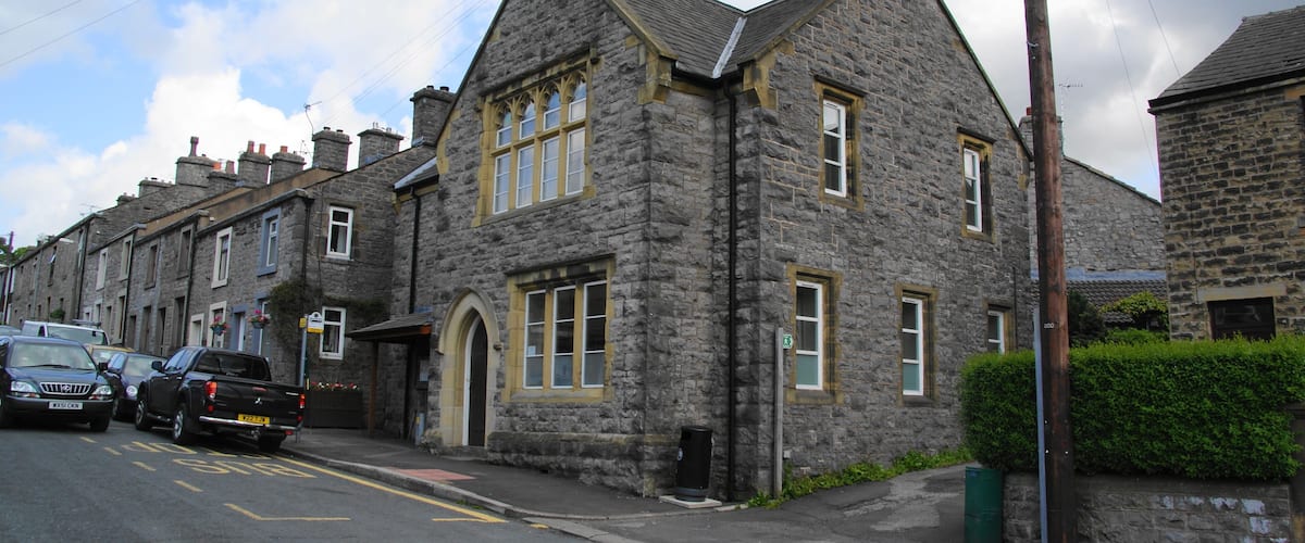 A stone building with a steep roof and multiple windows.