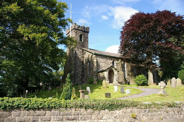 A stone church with a bell tower, surrounded by trees and a cemetery.