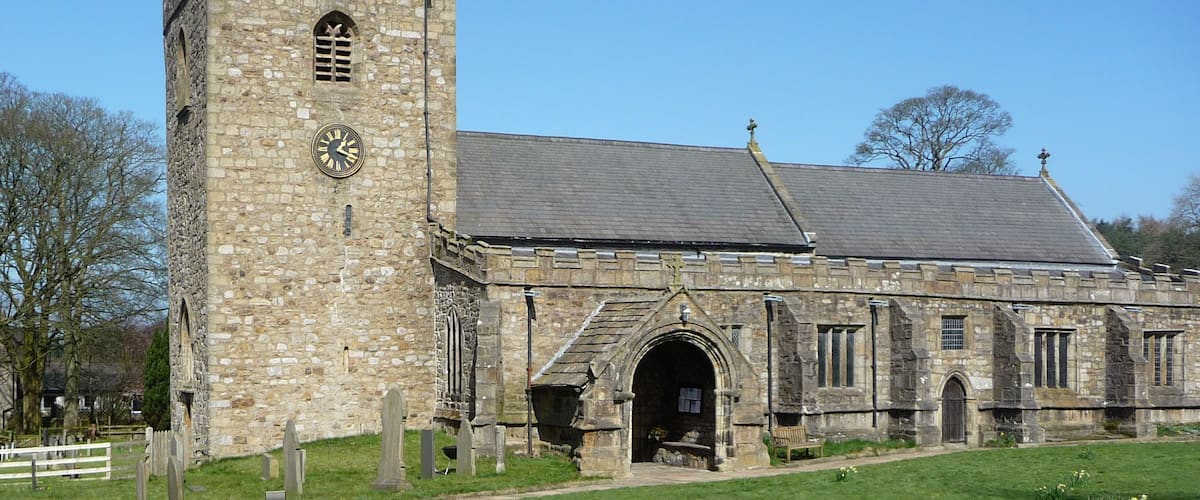 A historic stone church with a clock tower and a large arched entrance.