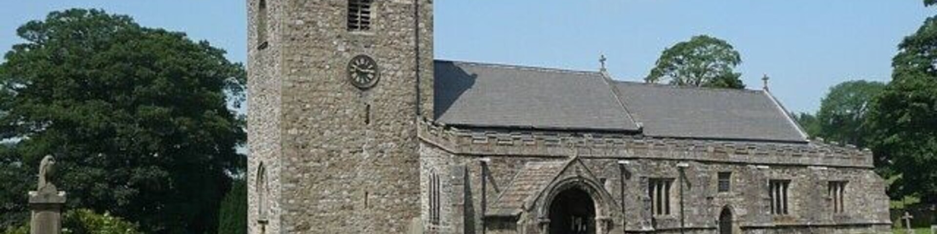 Una iglesia de piedra con un campanario y una entrada de arco grande.
