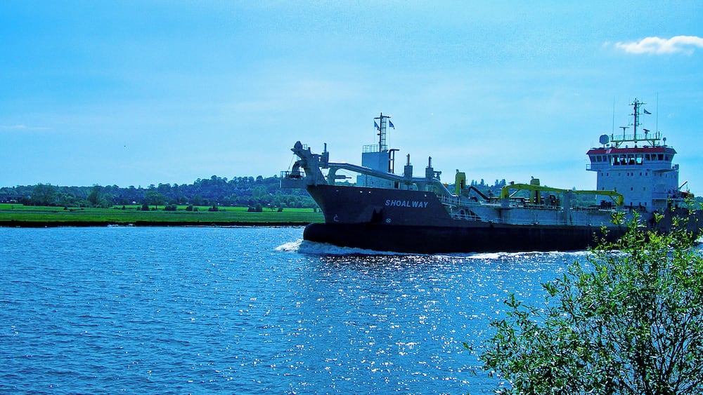 A large cargo ship named "Shoal Way" on a river.