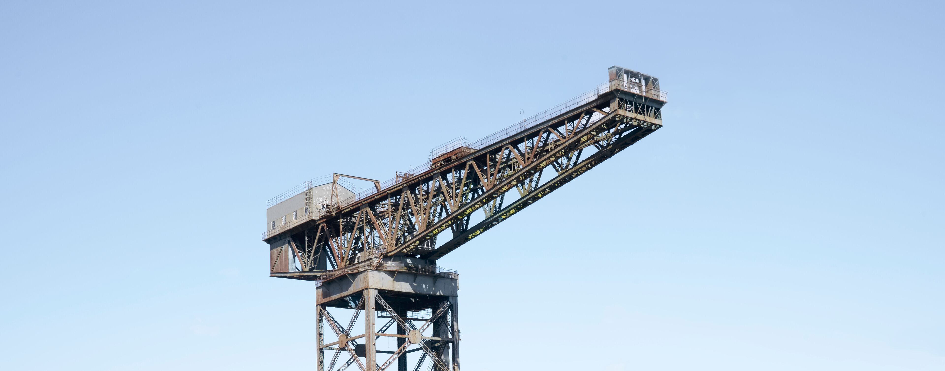 A large industrial crane with a long horizontal arm against a clear sky.