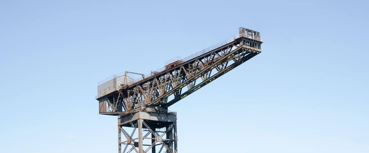 A large industrial crane with a long horizontal arm against a clear sky.