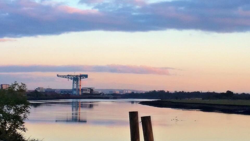 A river with a bridge and industrial structures in the background.