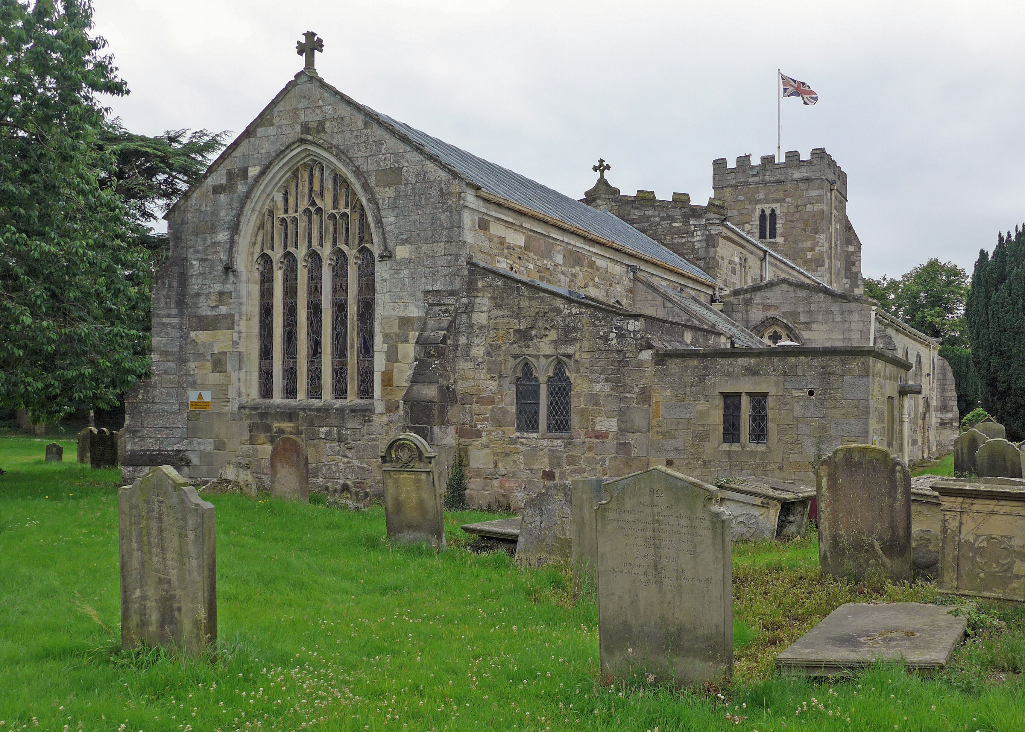 A historic stone church with a tall tower and a flag.