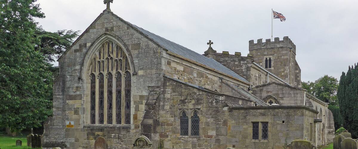 A historic stone church with a tall tower and a flag.