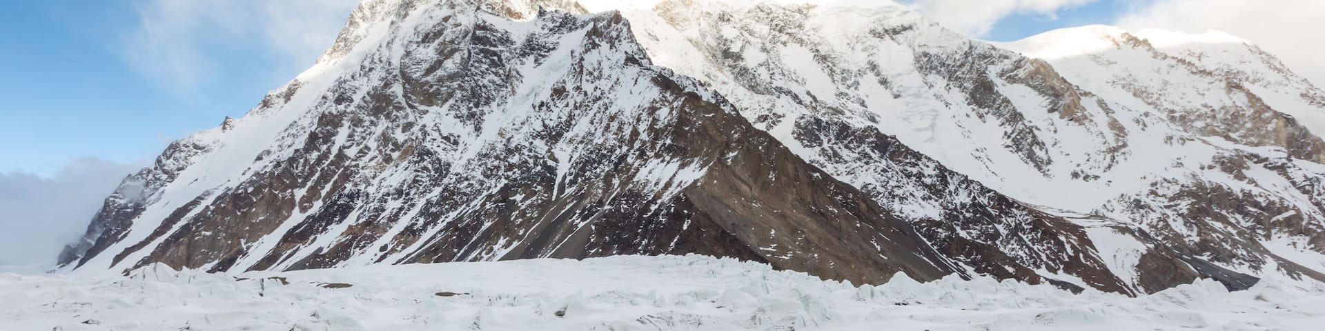 A snow-covered mountain peak with sharp ridges and a clear sky.