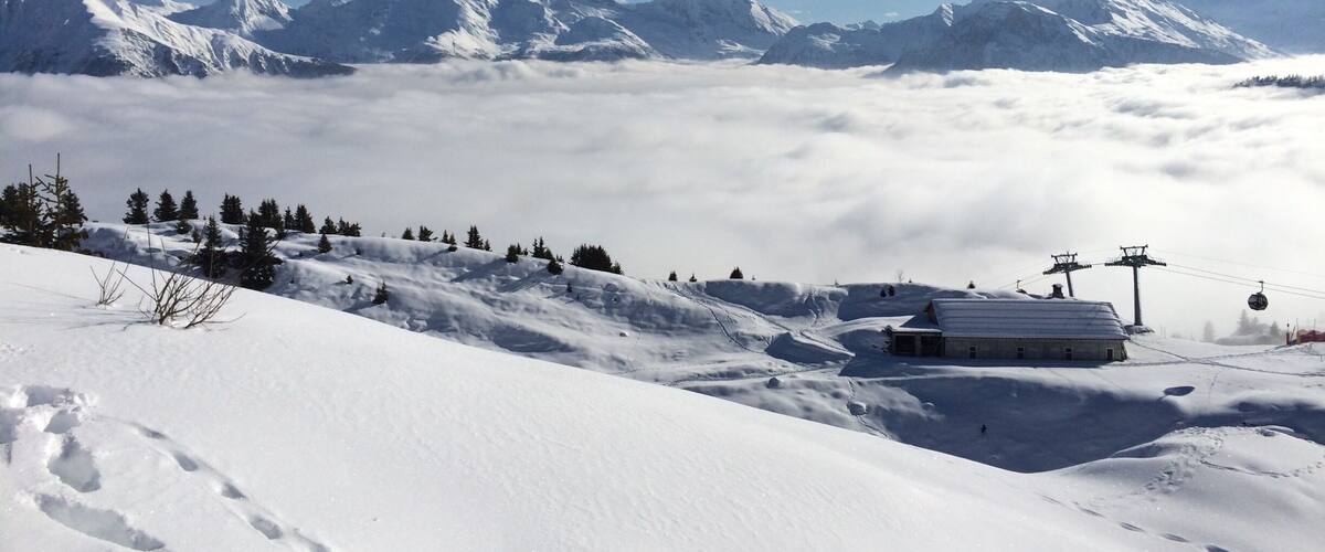A snow-covered mountain landscape with a ski lift, a cabin, and a clear sky.