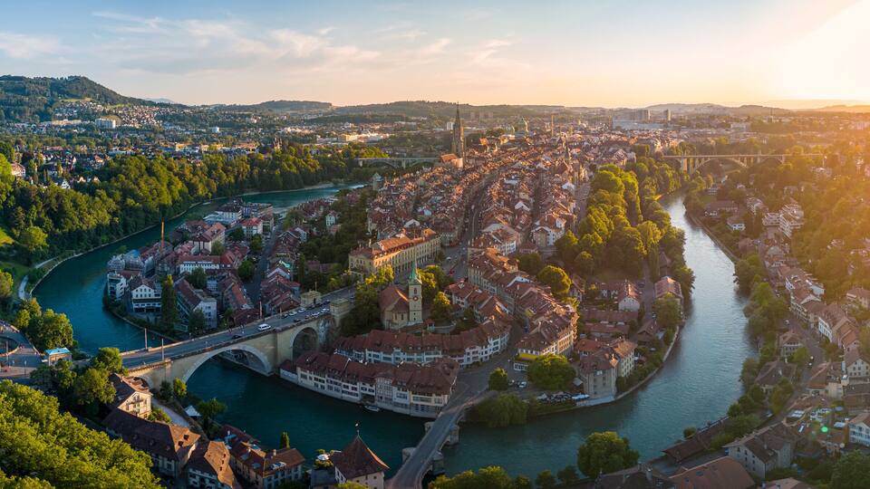 A river winding through a town with historic buildings and a bridge.