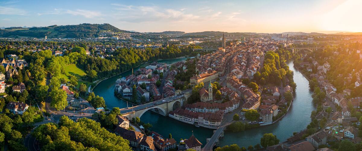A river winding through a town with historic buildings and a bridge.