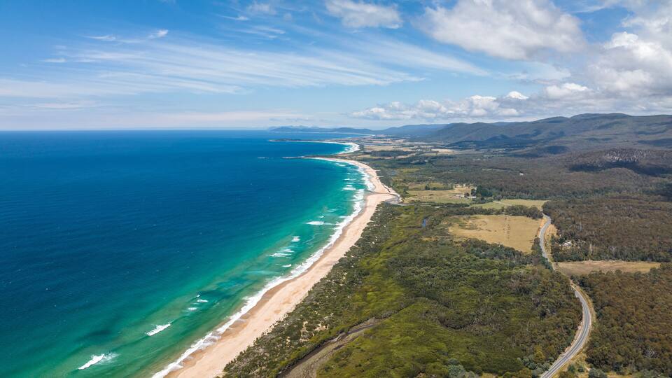Stunning high angle aerial panoramic drone view of Lagoons Beach Conservation Area and the A3 Tasman Highway near the village of Scamander on the east coast of Tasmania, Australia on a sunny day.