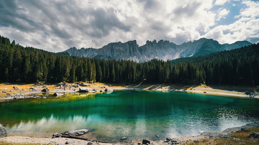 Un lac de montagne entouré d’une forêt dense et de montagnes escarpées.
