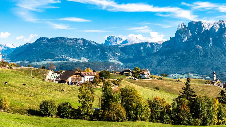 A mountainous landscape with a village, green fields, and a prominent church.