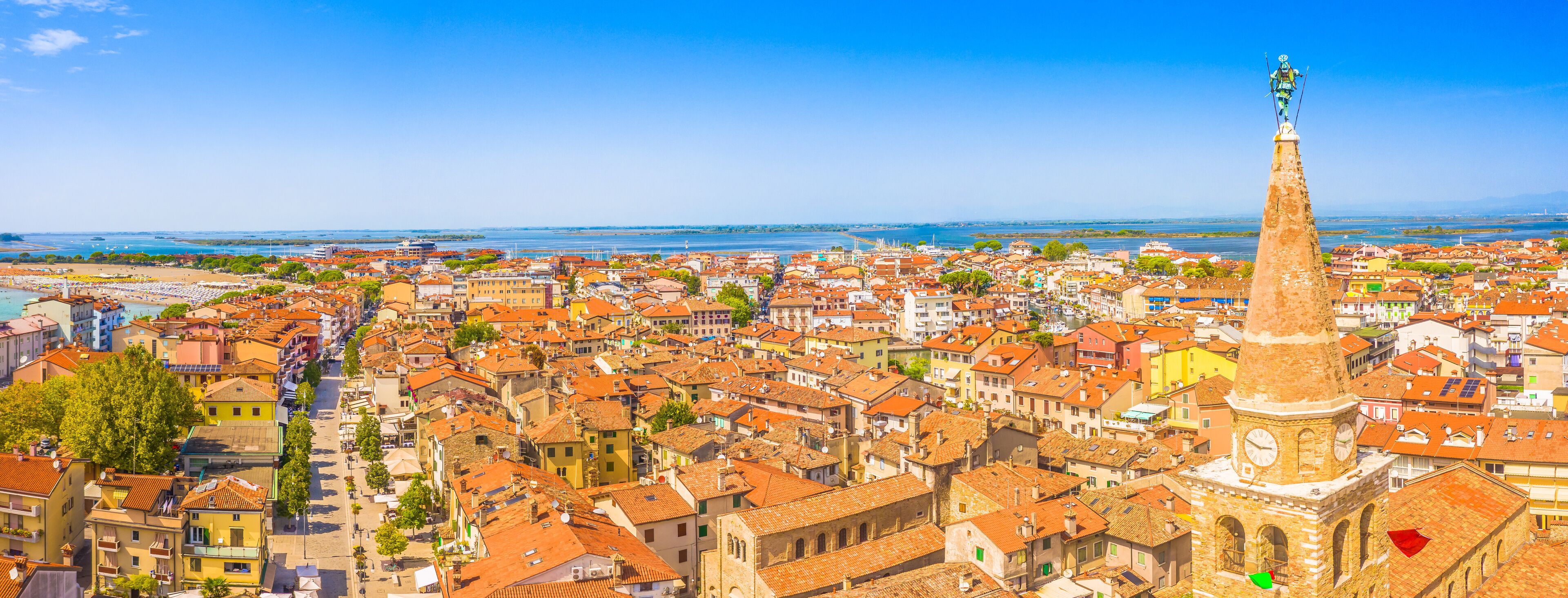 A panoramic aerial view of the old town of Grado, Italy, showcasing its charming historical architecture, red-tiled roofs, and coastal setting along the Adriatic in the Friuli-Venezia Giulia region