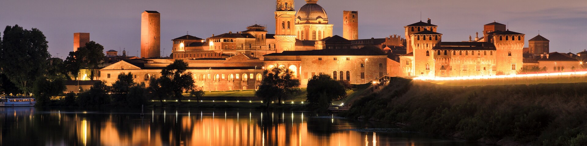 Europe Italy Mantova-Mantua ancient castle at the river reflecting in still waters at sunset highly illuminated by lights