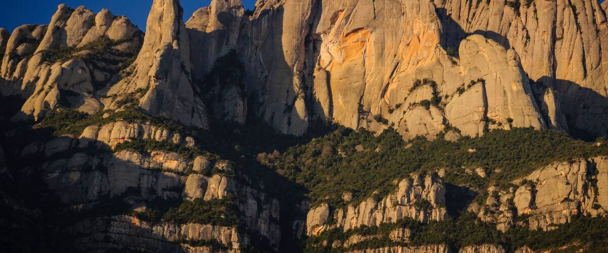 A rugged mountain range with prominent rock formations and sparse vegetation.