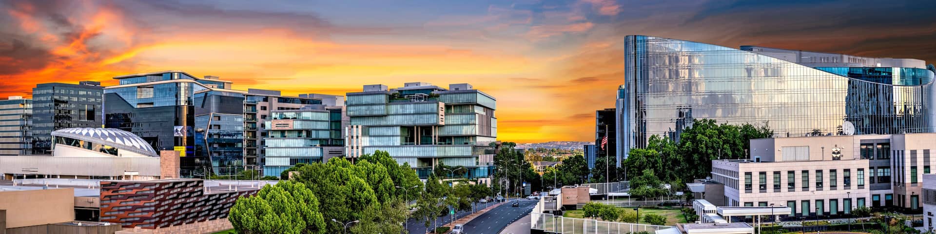 A cityscape with modern architecture and a sunset sky.