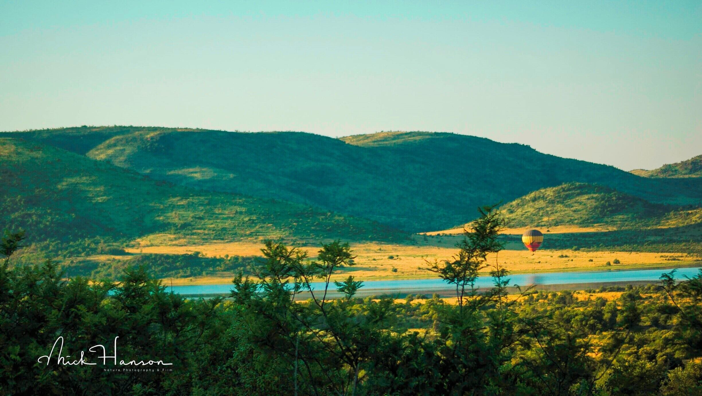 Morning drive through Pilanesberg National Park with a balloon drifting along just above the crater floor.