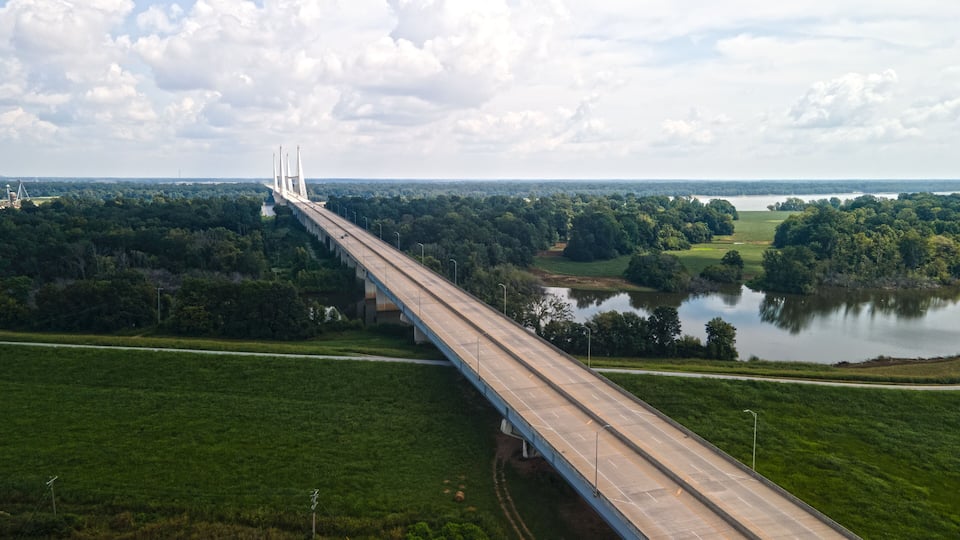 A long bridge spanning a river with a forested landscape on either side.
