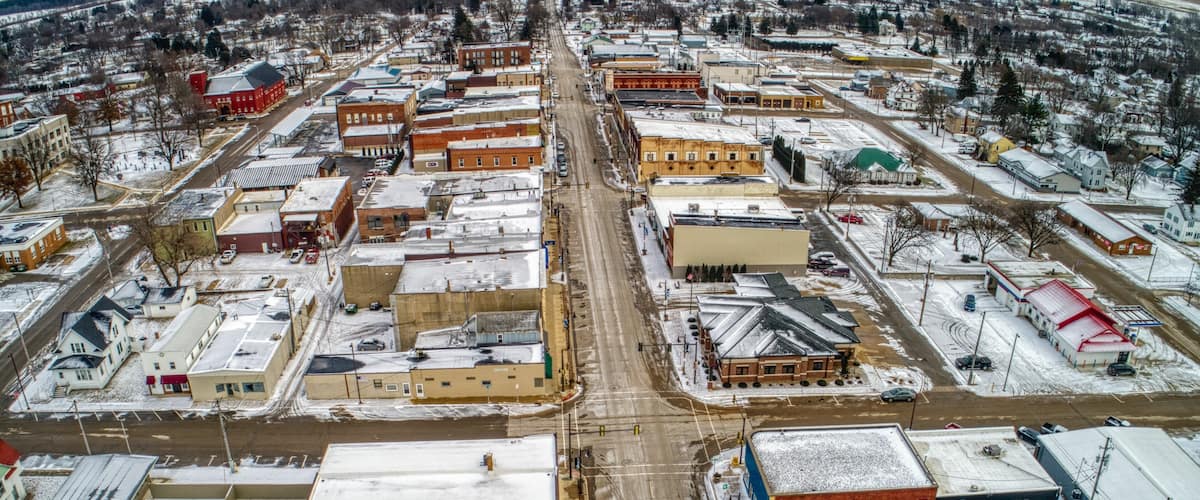 An aerial view of a snow-covered town with a mix of industrial and residential buildings.
