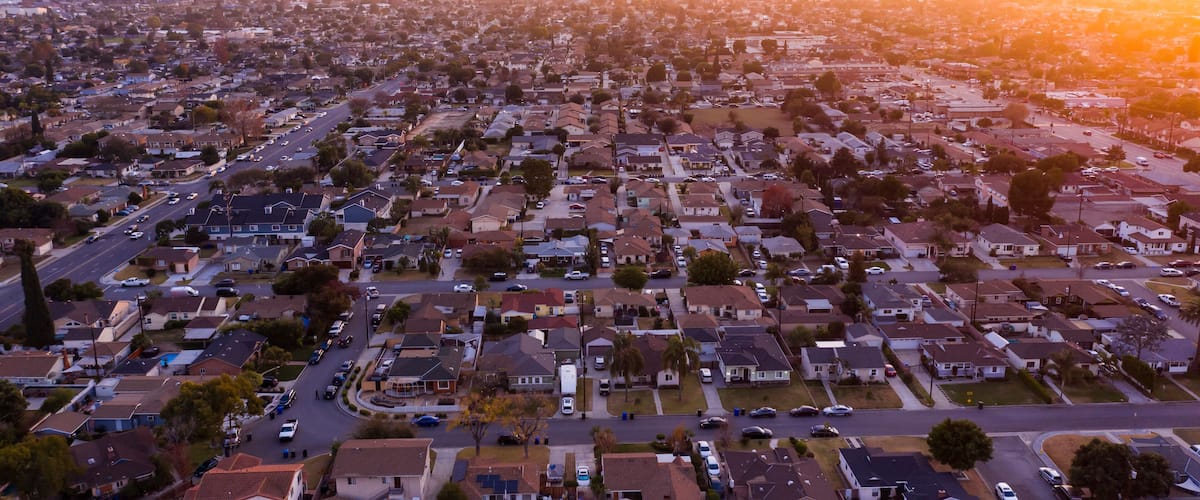 A suburban neighborhood with houses, streets, and a sunset.