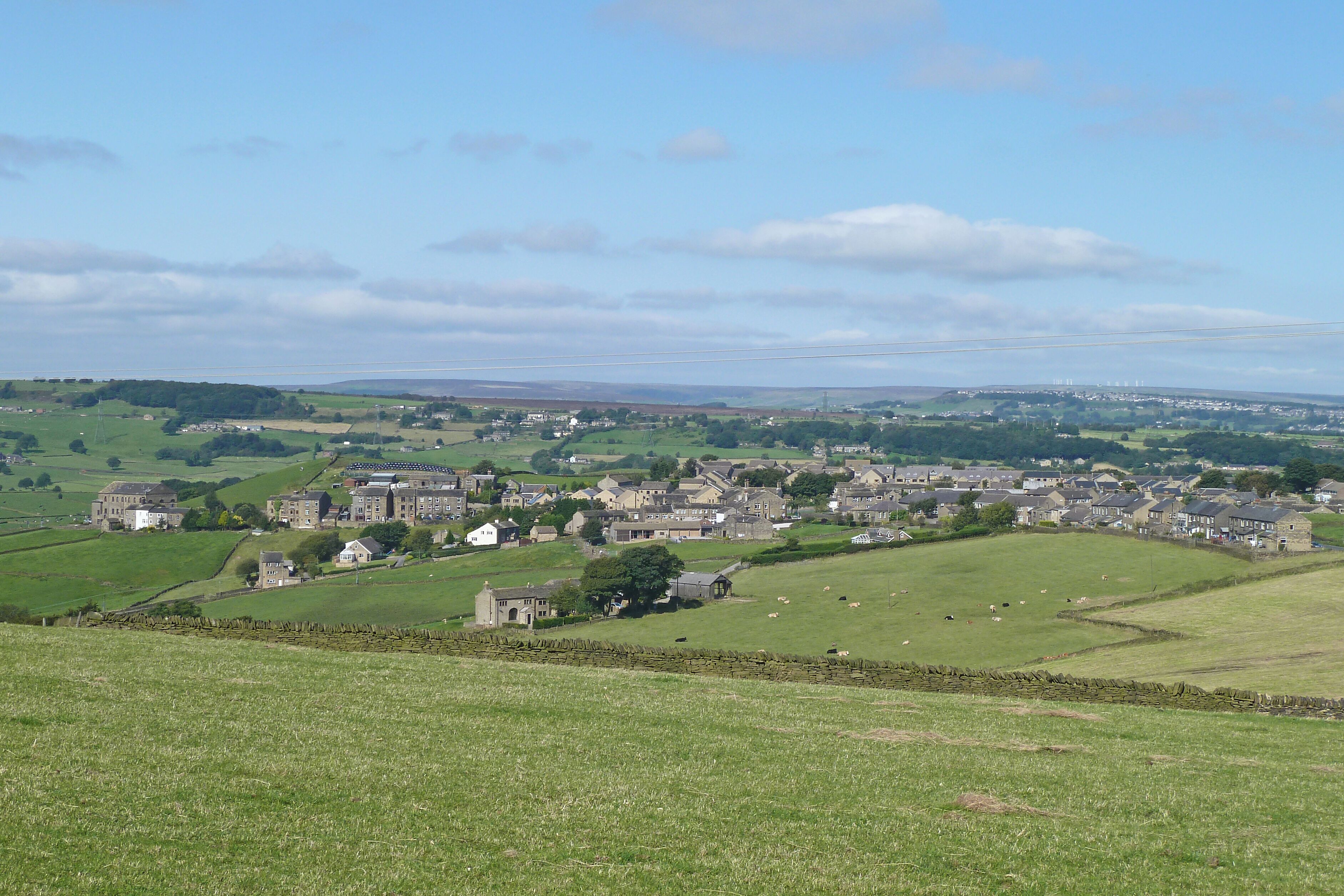 A rural landscape with a village, green fields, and stone walls.