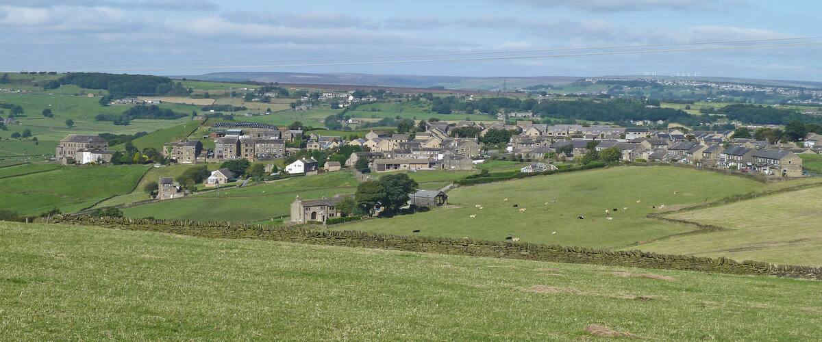 A rural landscape with a village, green fields, and stone walls.