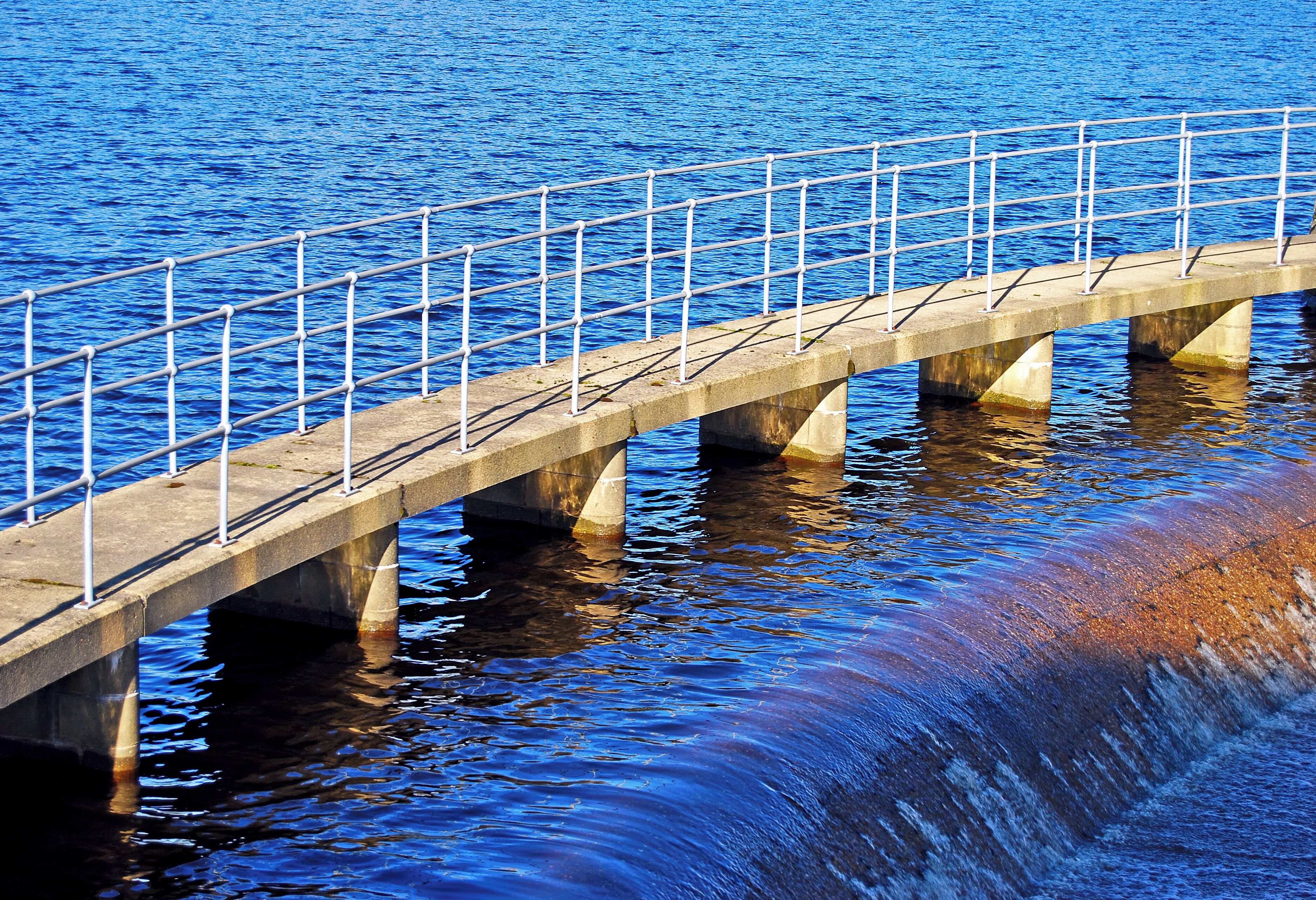 A concrete bridge over water with metal railings.