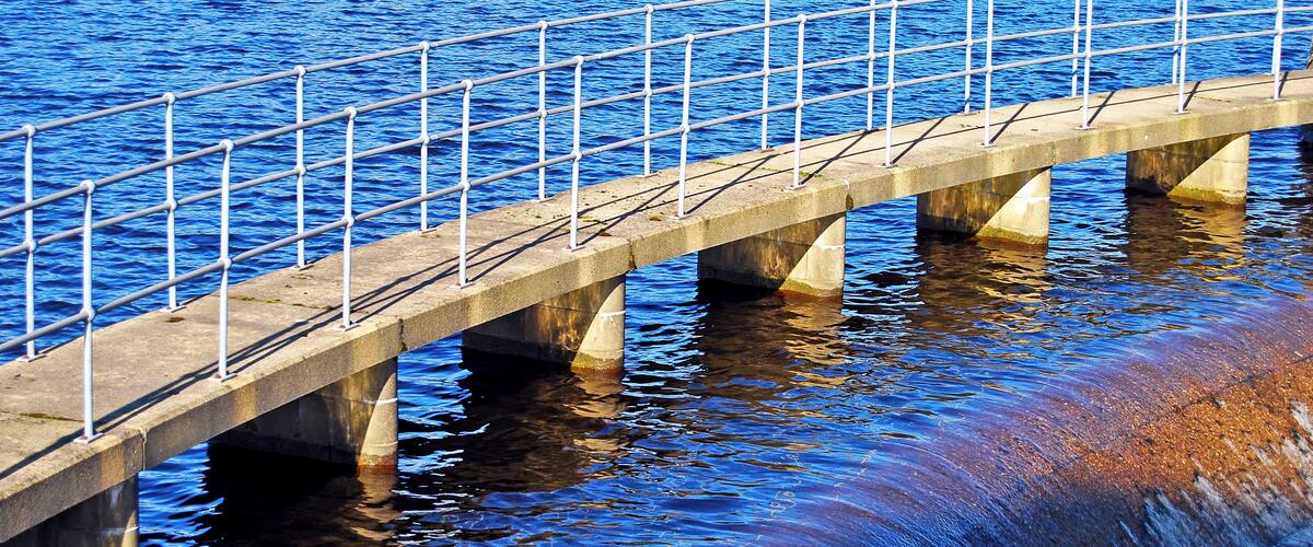 A concrete bridge over water with metal railings.