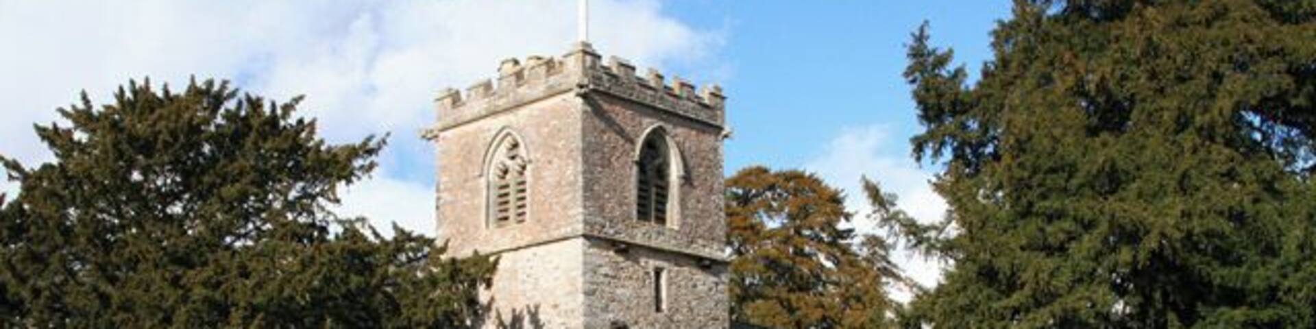 Feniton: St AndrewÂs church. The stumpy tower is almost dominated by the yew trees in the churchyard. Looking north east