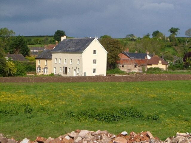 Feniton Mills from Fenny Bridge. Former mill buildings, together with other housing in Fenny Bridges, seen from the old A30 bridge over the River Otter, with some building debris in the foreground.