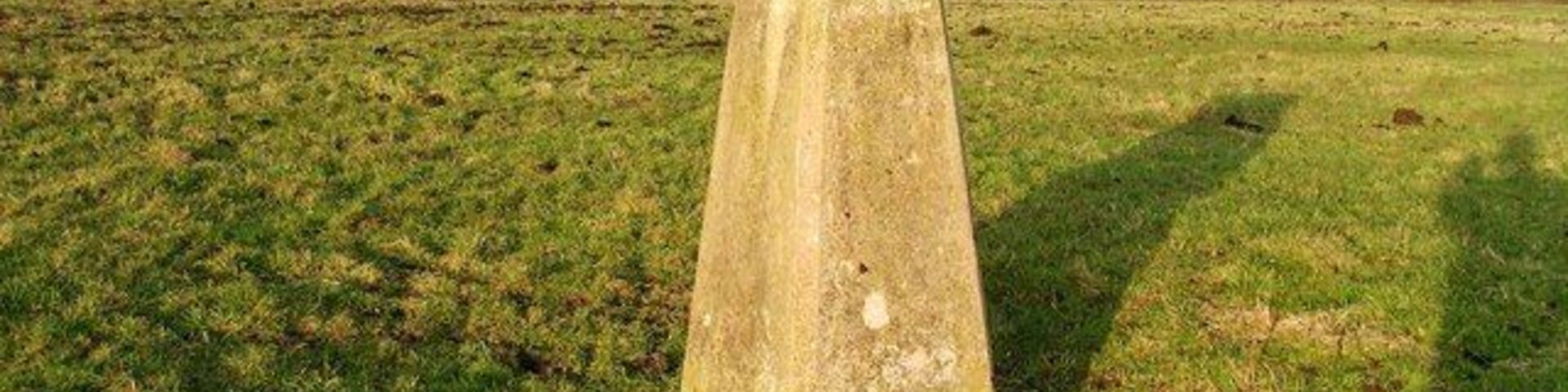 Un campo cubierto de hierba con una gran estructura de piedra erosionada en el centro.