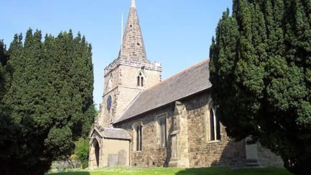 A church with a tall spire and a stone building.